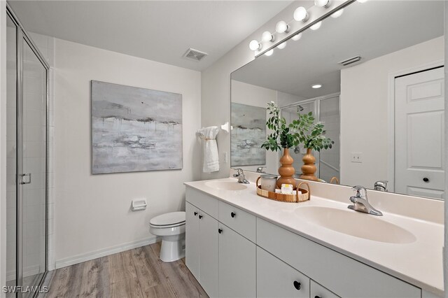 bathroom with walk in shower, vanity, hardwood / wood-style floors, and toilet