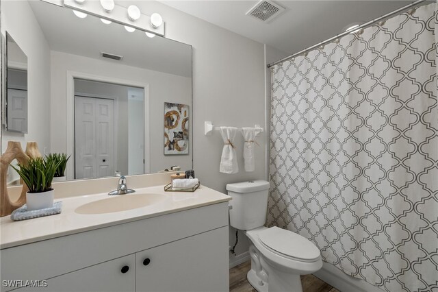 bathroom with curtained shower, wood-type flooring, vanity, and toilet