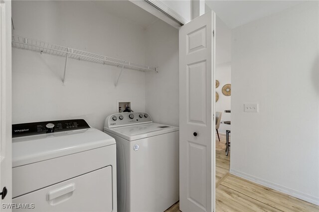 laundry area with light hardwood / wood-style floors and washing machine and dryer