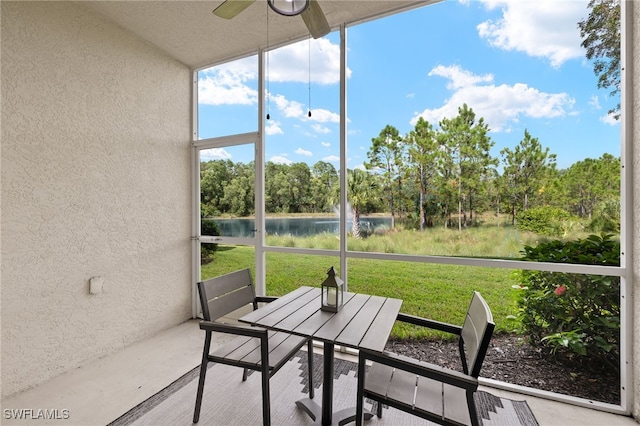 unfurnished sunroom featuring a water view and ceiling fan