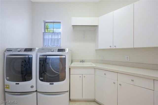 clothes washing area featuring a sink, cabinet space, and washer and dryer