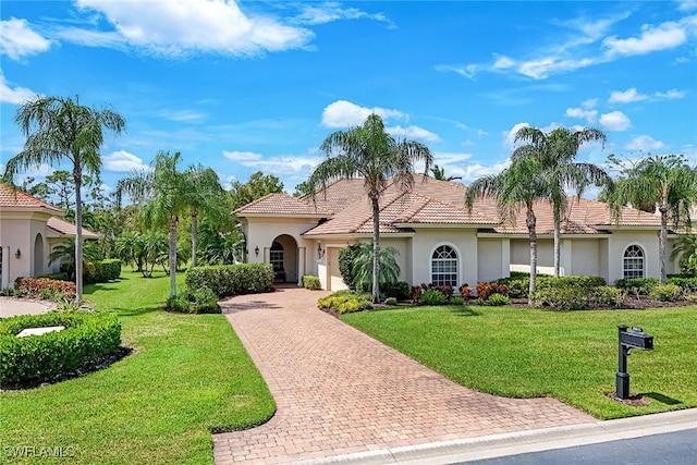 mediterranean / spanish-style house with a tiled roof, a front lawn, decorative driveway, and stucco siding