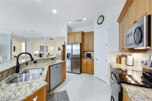 kitchen with light stone counters, stainless steel appliances, visible vents, decorative backsplash, and a sink