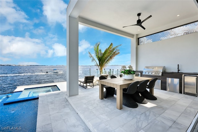 view of patio / terrace featuring ceiling fan, exterior kitchen, grilling area, a swimming pool with hot tub, and a water view