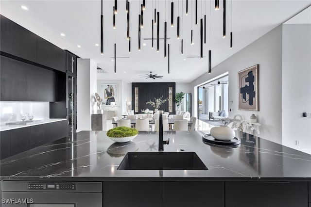 kitchen with sink, ceiling fan, and dark stone countertops