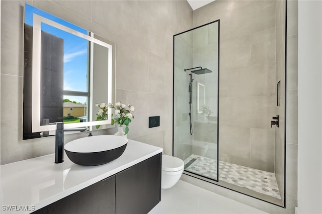 bathroom featuring vanity, tile patterned floors, toilet, tiled shower, and tile walls