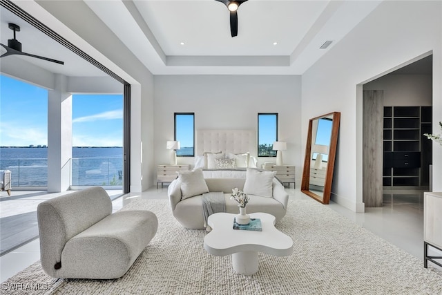 bedroom with a raised ceiling, ceiling fan, a water view, and a walk in closet