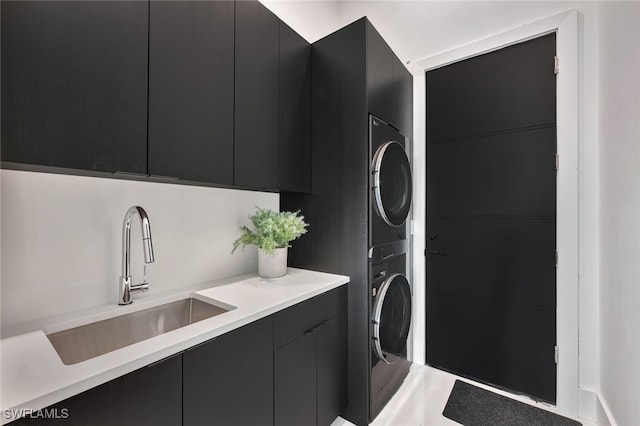 laundry room with cabinets, stacked washer / dryer, and sink