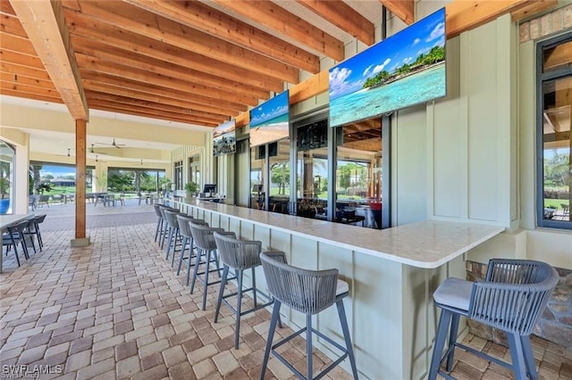 bar featuring beam ceiling and a healthy amount of sunlight