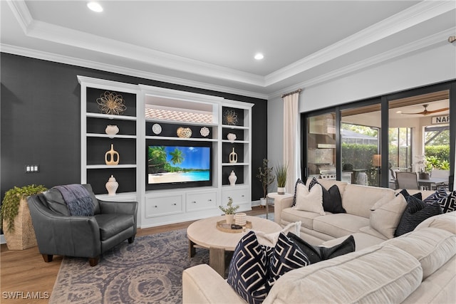 living room with ceiling fan, hardwood / wood-style flooring, a tray ceiling, and ornamental molding