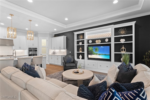 living room featuring light hardwood / wood-style flooring, a tray ceiling, and crown molding