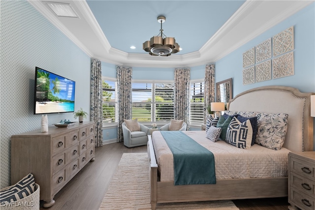 bedroom featuring light hardwood / wood-style floors, ornamental molding, a tray ceiling, and a notable chandelier