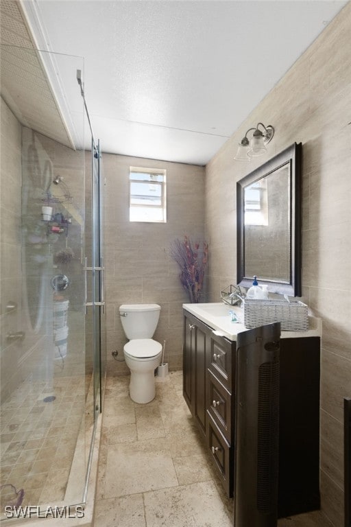 bathroom with vanity, tile walls, toilet, and an enclosed shower