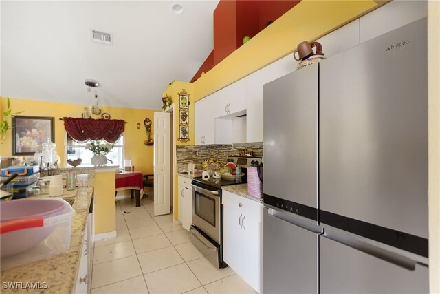 kitchen with light tile patterned flooring, vaulted ceiling, white cabinetry, stainless steel appliances, and backsplash