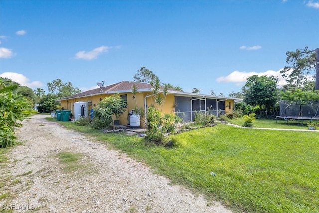 single story home featuring a sunroom, a trampoline, and a front yard