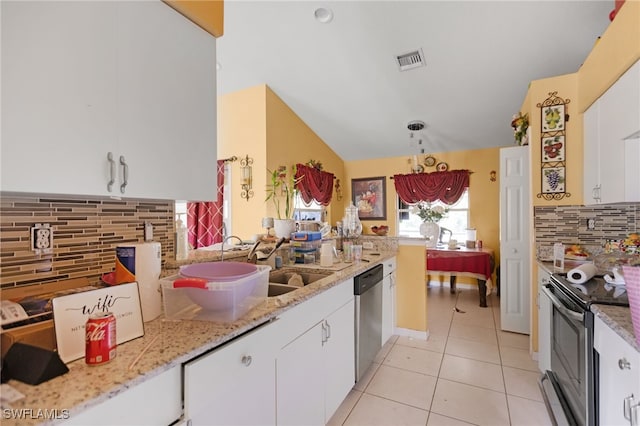 kitchen featuring appliances with stainless steel finishes, decorative backsplash, light stone counters, white cabinets, and lofted ceiling