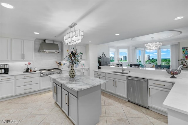 kitchen with a kitchen island, wall chimney exhaust hood, hanging light fixtures, stainless steel appliances, and sink