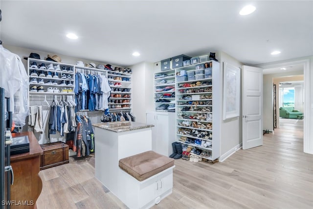 walk in closet with light hardwood / wood-style floors