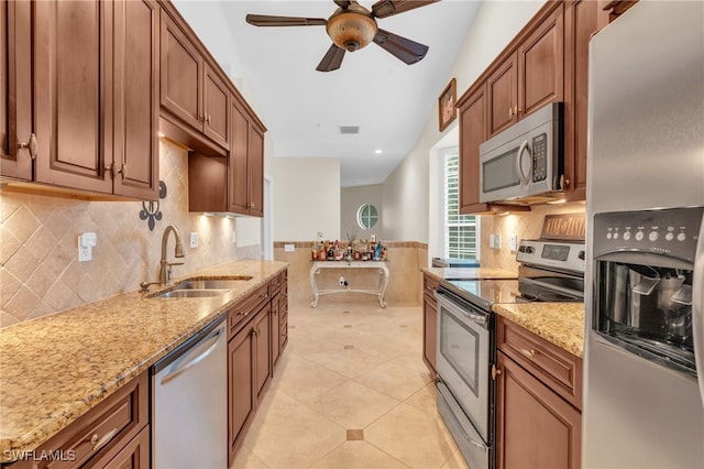 kitchen with ceiling fan, light tile patterned flooring, sink, appliances with stainless steel finishes, and light stone countertops