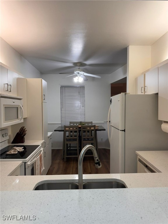 kitchen with ceiling fan, light stone counters, sink, white appliances, and dark hardwood / wood-style floors