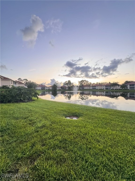 yard at dusk featuring a water view