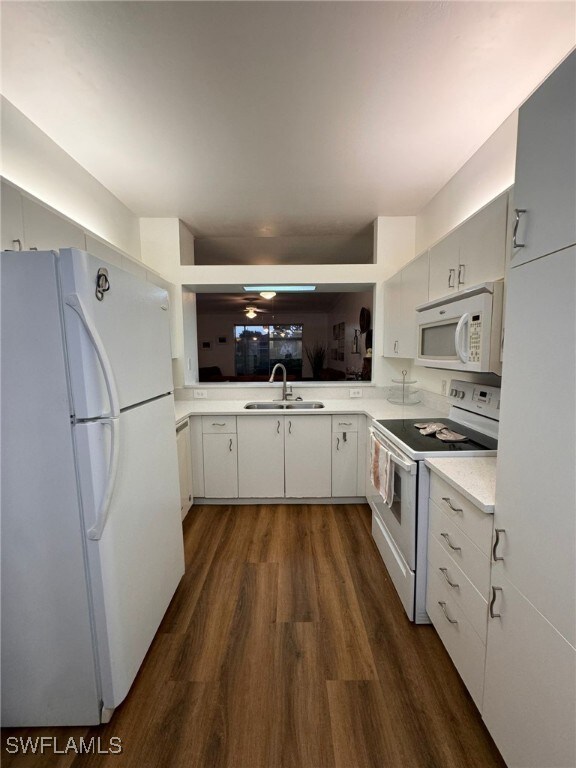 kitchen with dark hardwood / wood-style floors, sink, white appliances, and white cabinetry