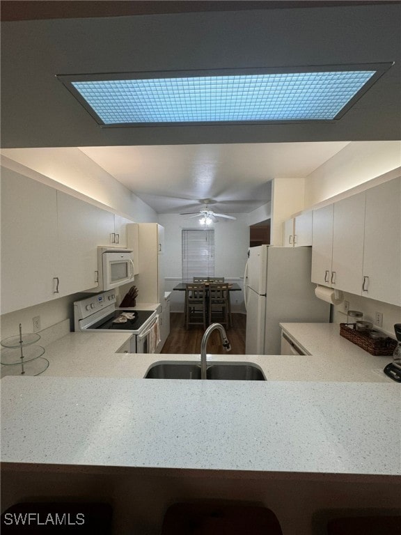 kitchen with white appliances, sink, ceiling fan, and kitchen peninsula