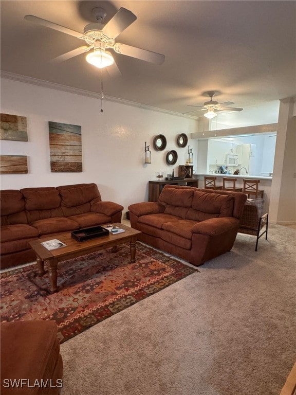 living room with ceiling fan, ornamental molding, and carpet