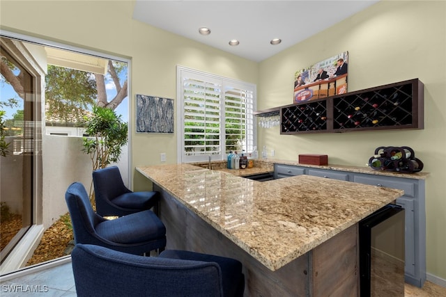 bar with light stone countertops, wine cooler, and plenty of natural light