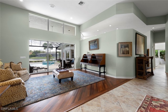 living room featuring light wood-type flooring, a healthy amount of sunlight, and a high ceiling