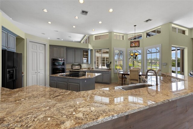 kitchen featuring hanging light fixtures, sink, gray cabinetry, black appliances, and a towering ceiling