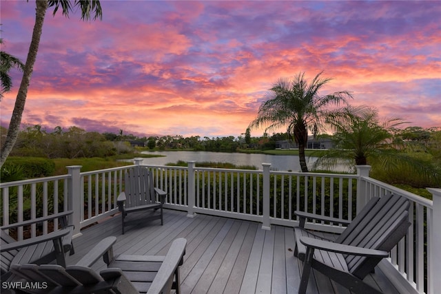 deck at dusk featuring a water view