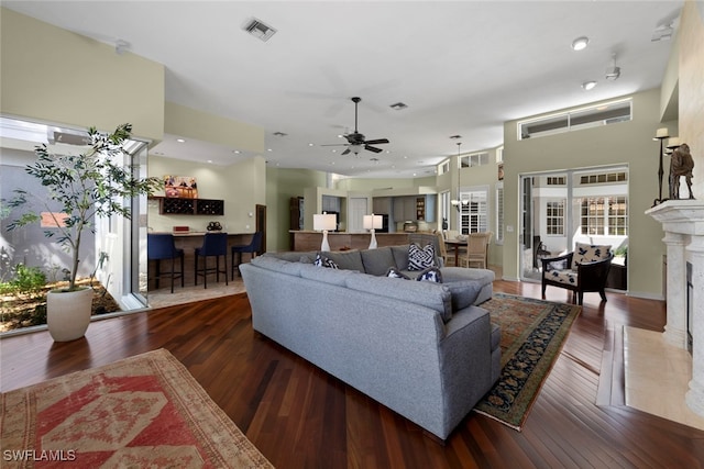 living room with ceiling fan, a premium fireplace, and dark hardwood / wood-style flooring