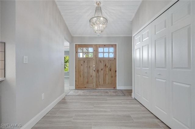 entrance foyer with light wood-type flooring, a chandelier, and wooden ceiling