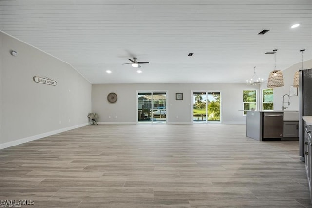 unfurnished living room with light hardwood / wood-style floors, ceiling fan with notable chandelier, and vaulted ceiling