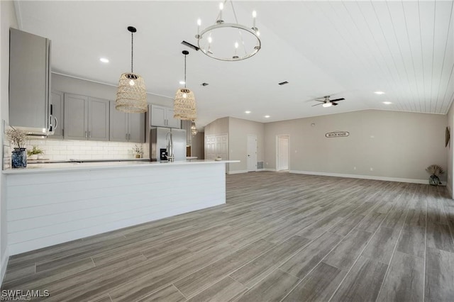 kitchen featuring ceiling fan with notable chandelier, gray cabinetry, hardwood / wood-style floors, and backsplash