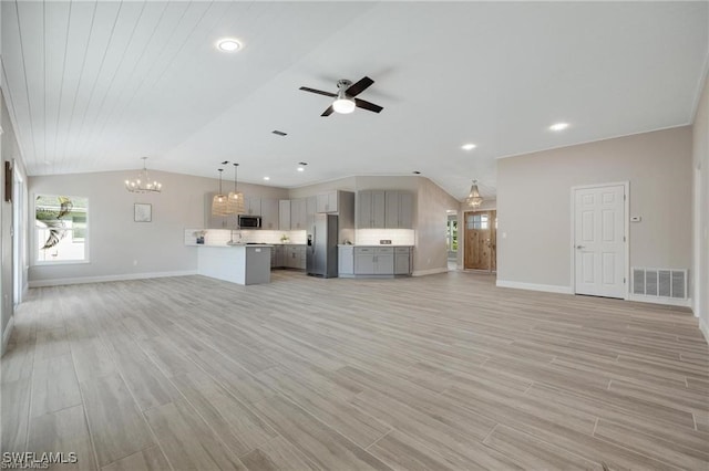 unfurnished living room featuring ceiling fan with notable chandelier, light hardwood / wood-style floors, and lofted ceiling