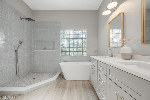 bathroom with plus walk in shower, hardwood / wood-style flooring, and vanity