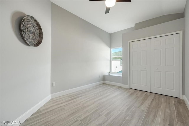 unfurnished bedroom with a closet, vaulted ceiling, light hardwood / wood-style floors, and ceiling fan