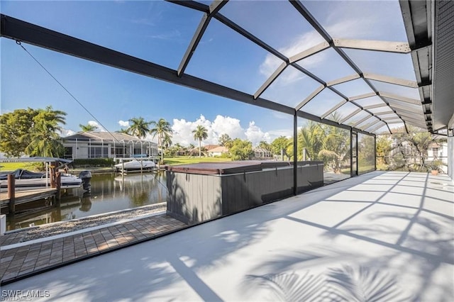 view of patio featuring glass enclosure, a boat dock, and a water view