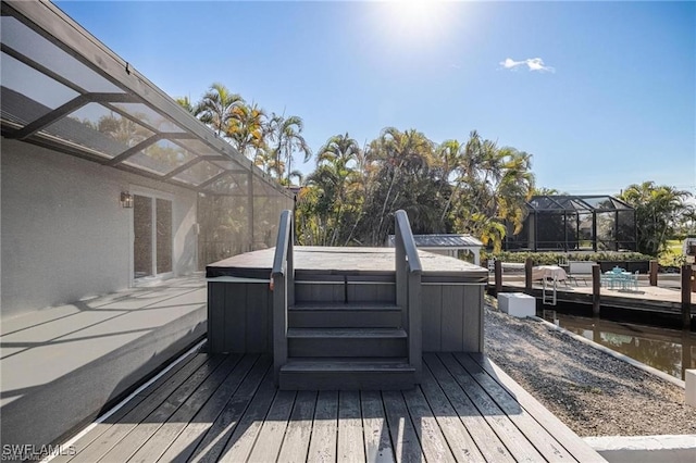 wooden terrace featuring a water view, a lanai, and a hot tub