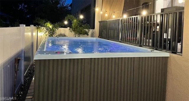 pool at night with a hot tub