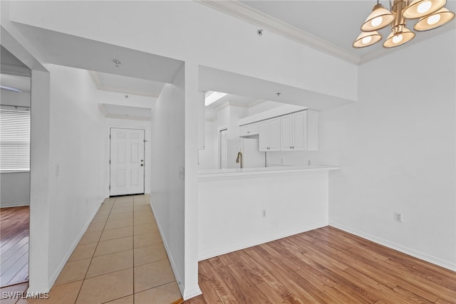 interior space with a notable chandelier, light wood-type flooring, and crown molding