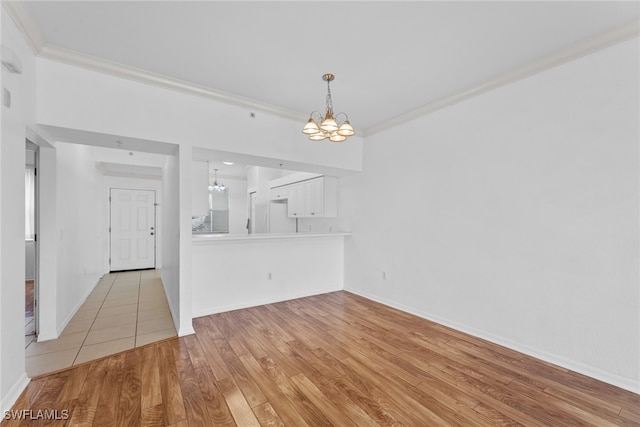 unfurnished dining area with light wood-type flooring, crown molding, and an inviting chandelier