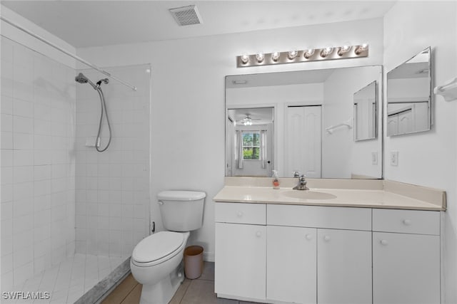 bathroom featuring tile patterned floors, tiled shower, ceiling fan, vanity, and toilet