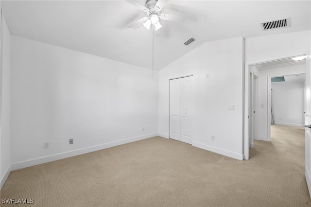 unfurnished bedroom featuring ceiling fan, light colored carpet, lofted ceiling, and a closet