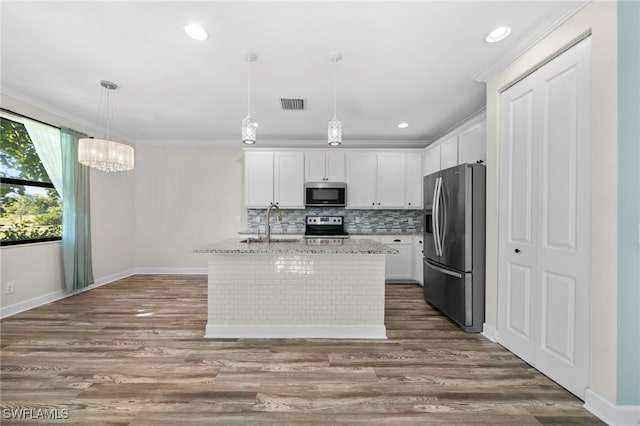 kitchen with appliances with stainless steel finishes, hanging light fixtures, an island with sink, and white cabinets