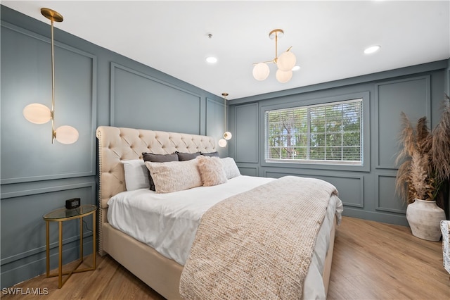 bedroom with a notable chandelier and light wood-type flooring