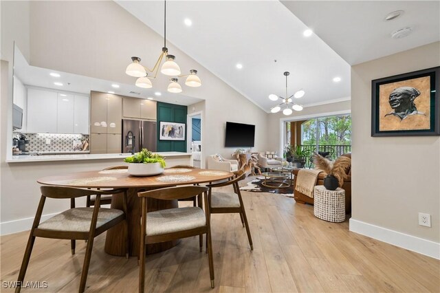 dining area featuring ornamental molding, light hardwood / wood-style floors, a chandelier, and high vaulted ceiling