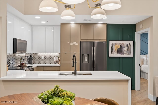 kitchen featuring white cabinets, kitchen peninsula, appliances with stainless steel finishes, and hanging light fixtures